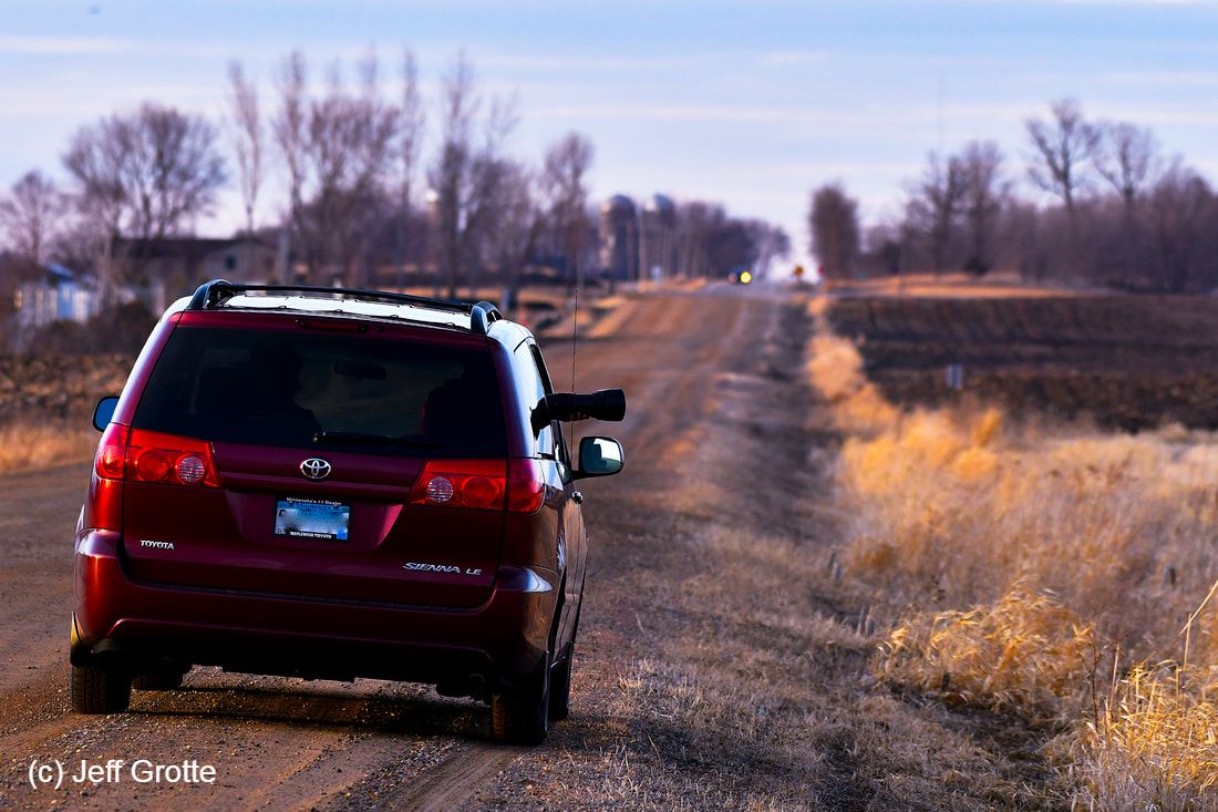 a vehicle parked on a gravel road with a camera sticking out one of the windows.