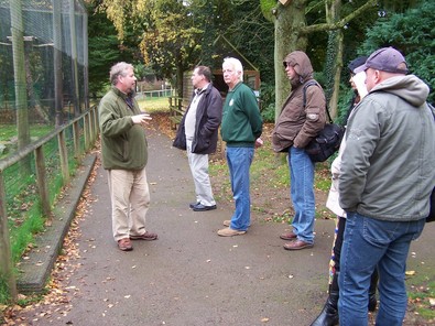 People standing and listening to a speaker outside an aviary at the hawk conservancy trust.