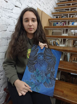 A teenage Ukrainian girl holding up her owl art.
